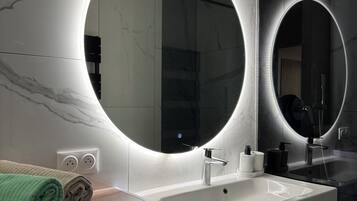 Une salle de bain moderne avec un grand miroir, un lavabo et un lave-linge.