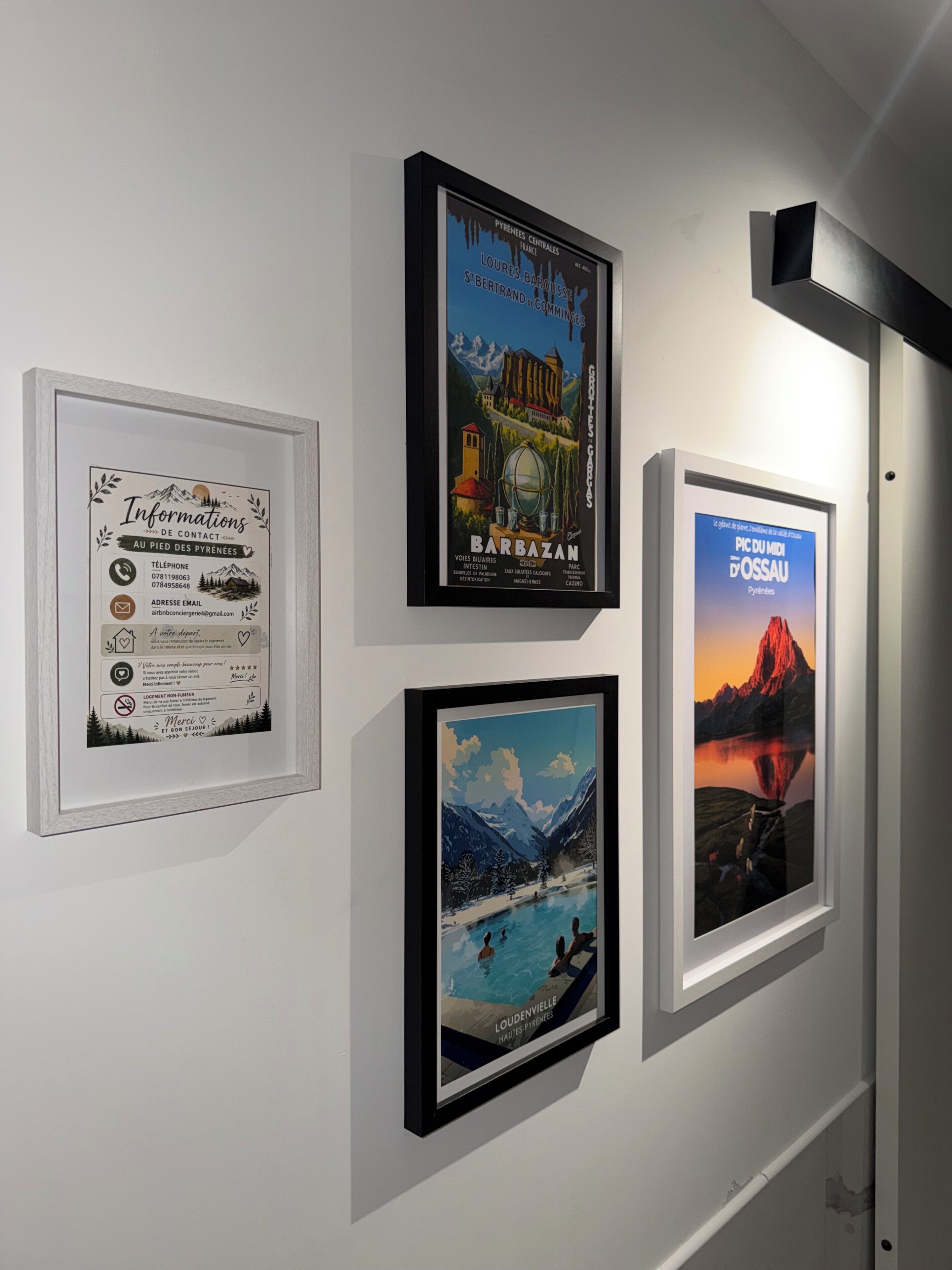 Eine Wand mit vier gerahmten Objekten: einer Karte mit Kontaktinformationen, ein Barbazan-Poster, ein Loudenville-Poster und ein Pic du Midi-Poster.