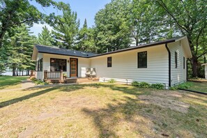 Ein eingeschossiges Haus mit Veranda, kleiner Terrasse und Rasen.