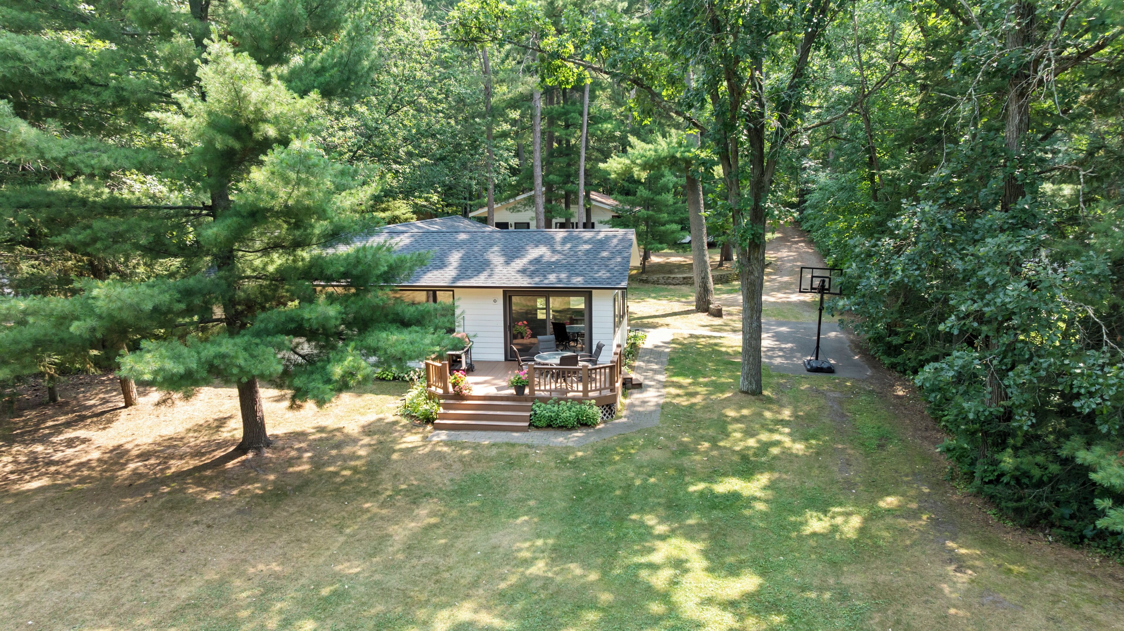 Une petite maison dotée d’une terrasse, entourée d’arbres denses.
