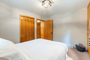 Ein Schlafzimmer mit einem Bett, zwei Holztüren, einer Lampe und einem kleinen Korb.