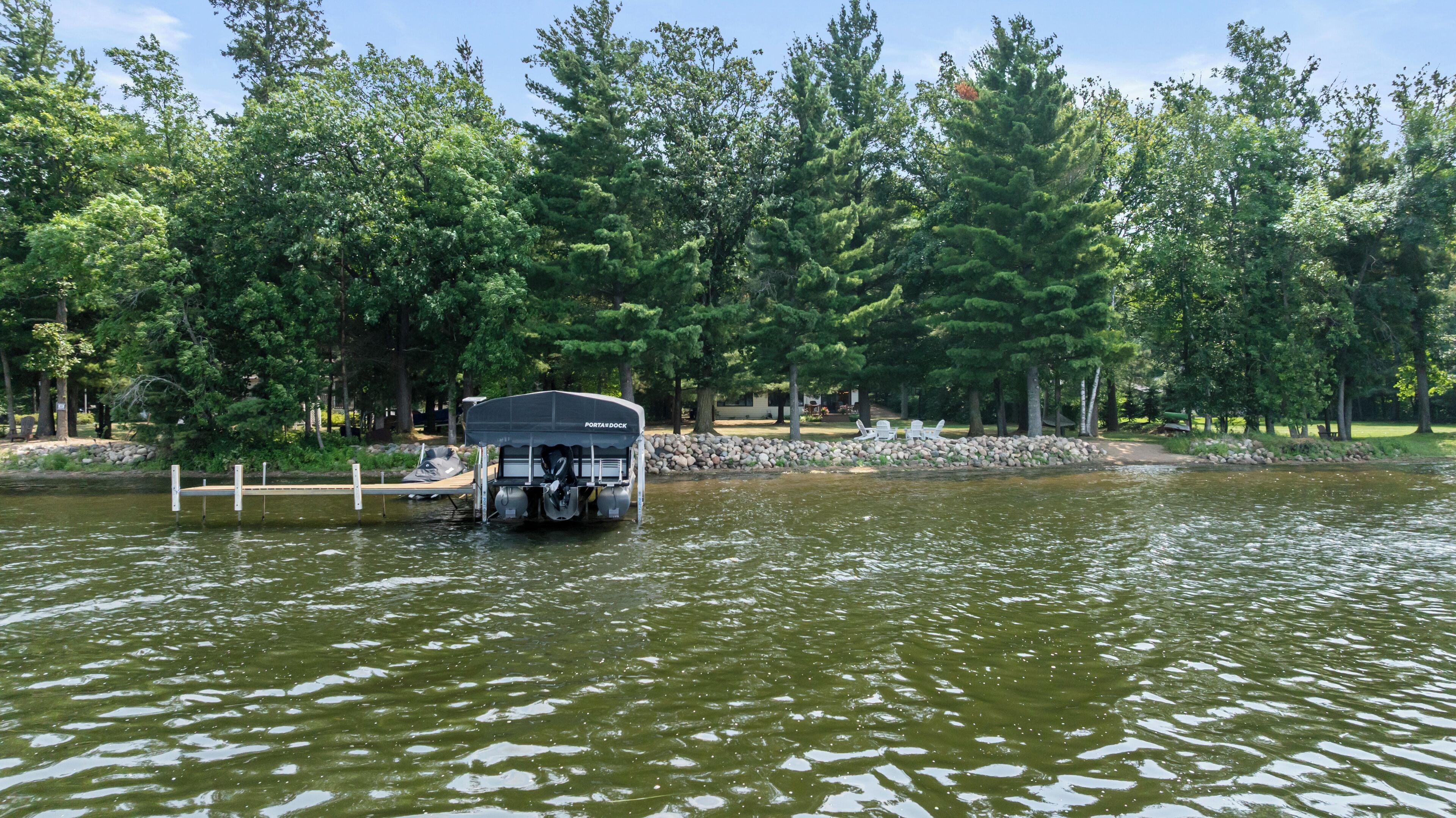 A boat docked at a marina with a stone wall and trees in the background.