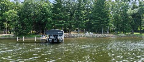 A boat docked at a marina with a stone wall and trees in the background.