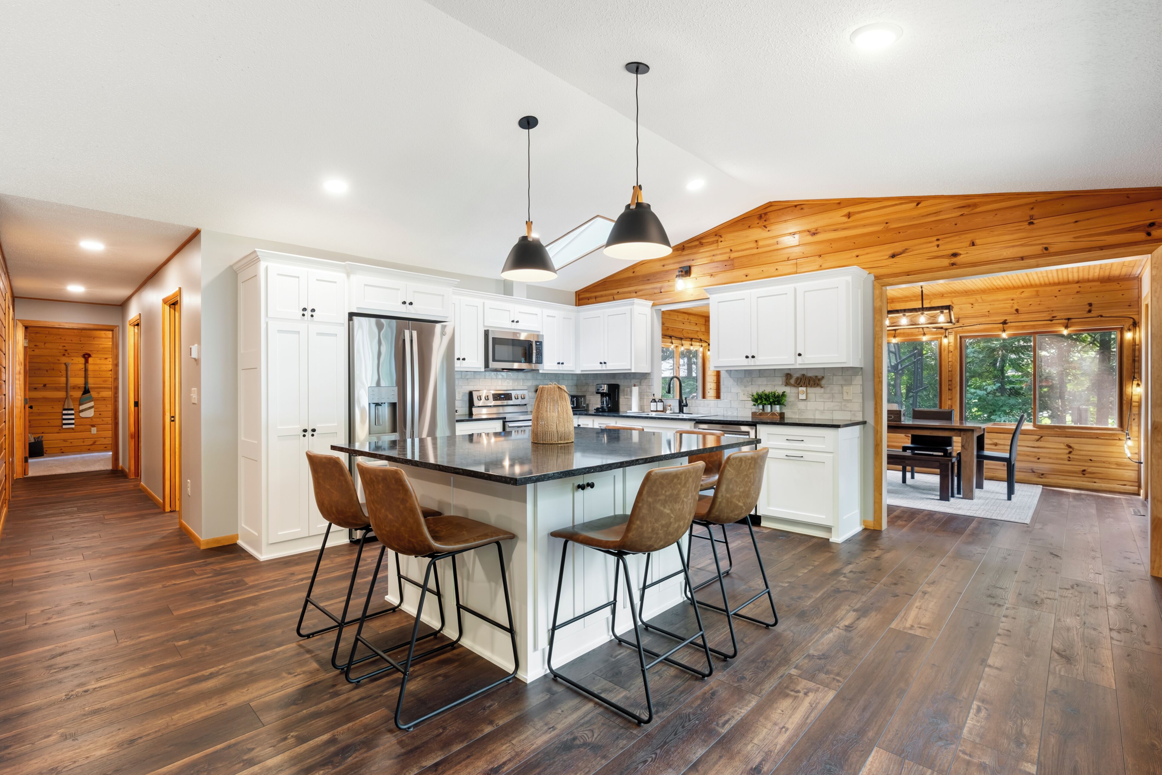 A modern kitchen with white cabinets, stainless steel appliances, and a central island with bar stools.