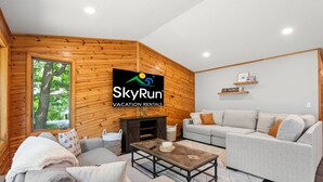 Ett mysigt vardagsrum med en väggpanel av trä, en soffa, ett soffbord och en tv-skärm som visar SkyRuns logotyp.