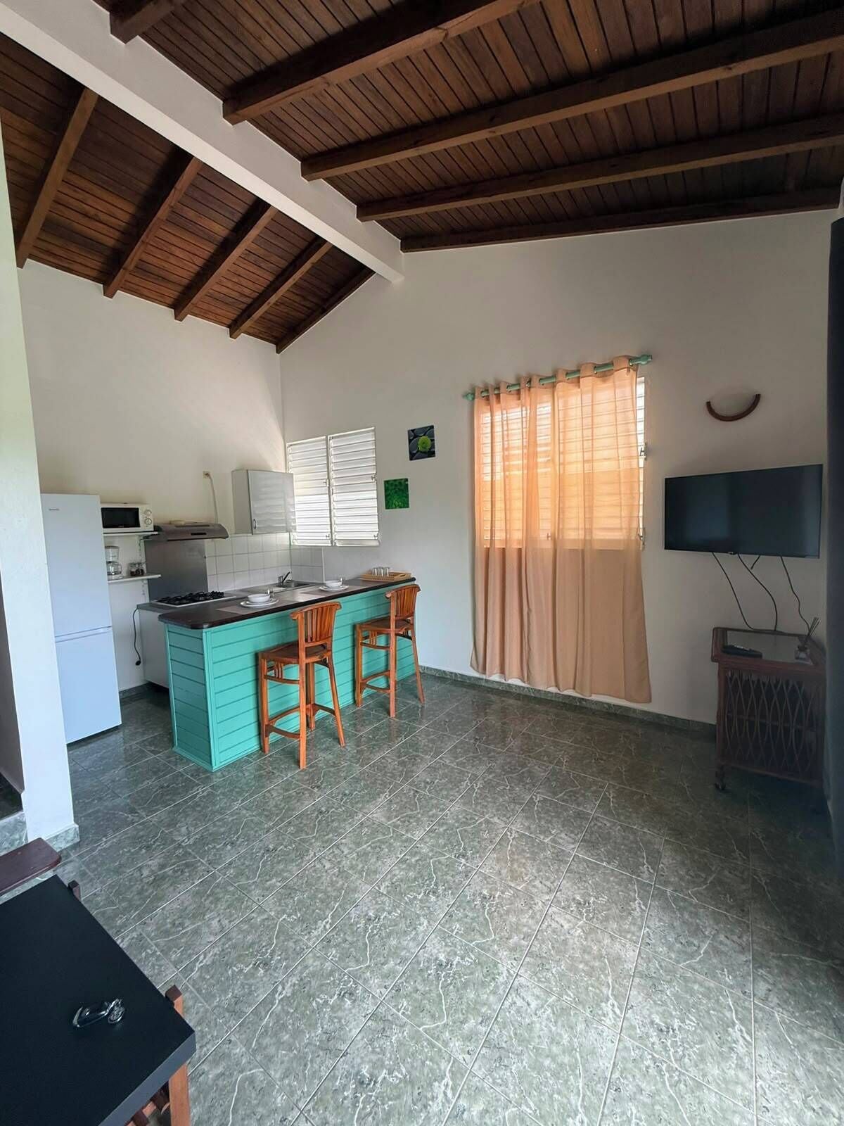 A kitchen with a bar area, a refrigerator, a microwave, and a television.
