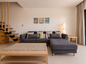 A modern living room with a grey sectional sofa, a wooden coffee table, and a staircase with wooden railings. - BORN Villa Laguna Vista Is Your Home Away From Home in Paradise! (Punta Cana)