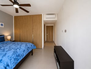 A bedroom with a bed, a ceiling fan, an air conditioning unit, a bedside lamp, and a wooden wardrobe. - BORN Villa Laguna Vista Is Your Home Away From Home in Paradise! (Punta Cana)
