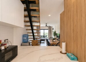 A modern kitchen with a built-in microwave, a water dispenser, and a wooden staircase. - BORN Villa Laguna Vista Is Your Home Away From Home in Paradise! (Punta Cana)