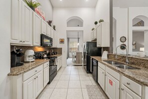 A kitchen with white cabinets, granite countertops, a coffee maker, and a refrigerator. - Sleeps 10*Private Pool*Games Room*Resort Amenities (Davenport)