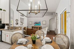 A modern kitchen with white cabinetry, a dining area with a wooden table set for four, and a living area with a sofa and a coffee table. - Sleeps 10*Private Pool*Games Room*Resort Amenities (Davenport)