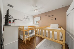 A room with bunk beds, a ceiling fan, a wall with motivational quotes, and a television on a stand. - Sleeps 10*Private Pool*Games Room*Resort Amenities (Davenport)