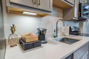 A modern kitchen with a stainless steel sink, a coffee maker, and a compact refrigerator. - Downtown Loft Retreat - Nearby Parking - 2F (Louisville)