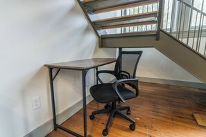 A corner office with a desk and chair, a window with a view of trees, and a staircase. - Downtown Loft Retreat - Nearby Parking - 2F (Louisville)