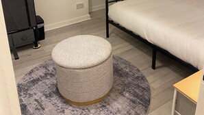 A bedroom with a bed, a round ottoman, a chair, and a wardrobe. - Prestige 3 bedroom flat in Cardiff (Cardiff)