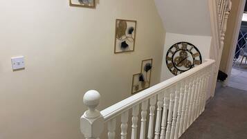 A staircase with a white balustrade, a wall-mounted clock, and decorative wall art.