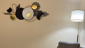A room with a grey armchair and ottoman on a patterned rug, a floor lamp, and a wall art piece. - Prestige 3 bedroom flat in Cardiff (Cardiff)
