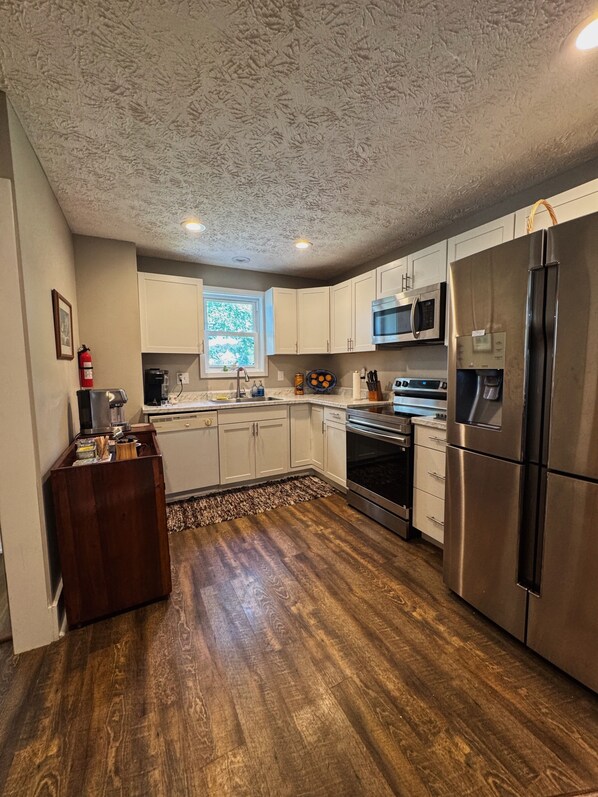 A kitchen with white cabinets, a stainless steel refrigerator, a microwave, and an oven.