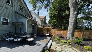 A wooden deck with outdoor furniture, a pergola, and a stone pathway.