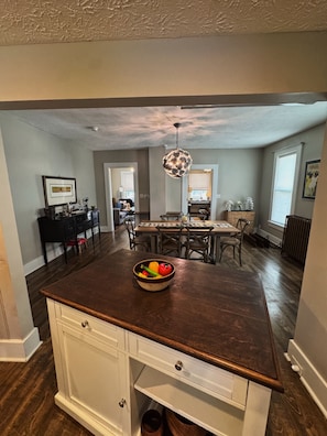A kitchen with a central island, wooden cabinets, and a dining area with chairs and a table.