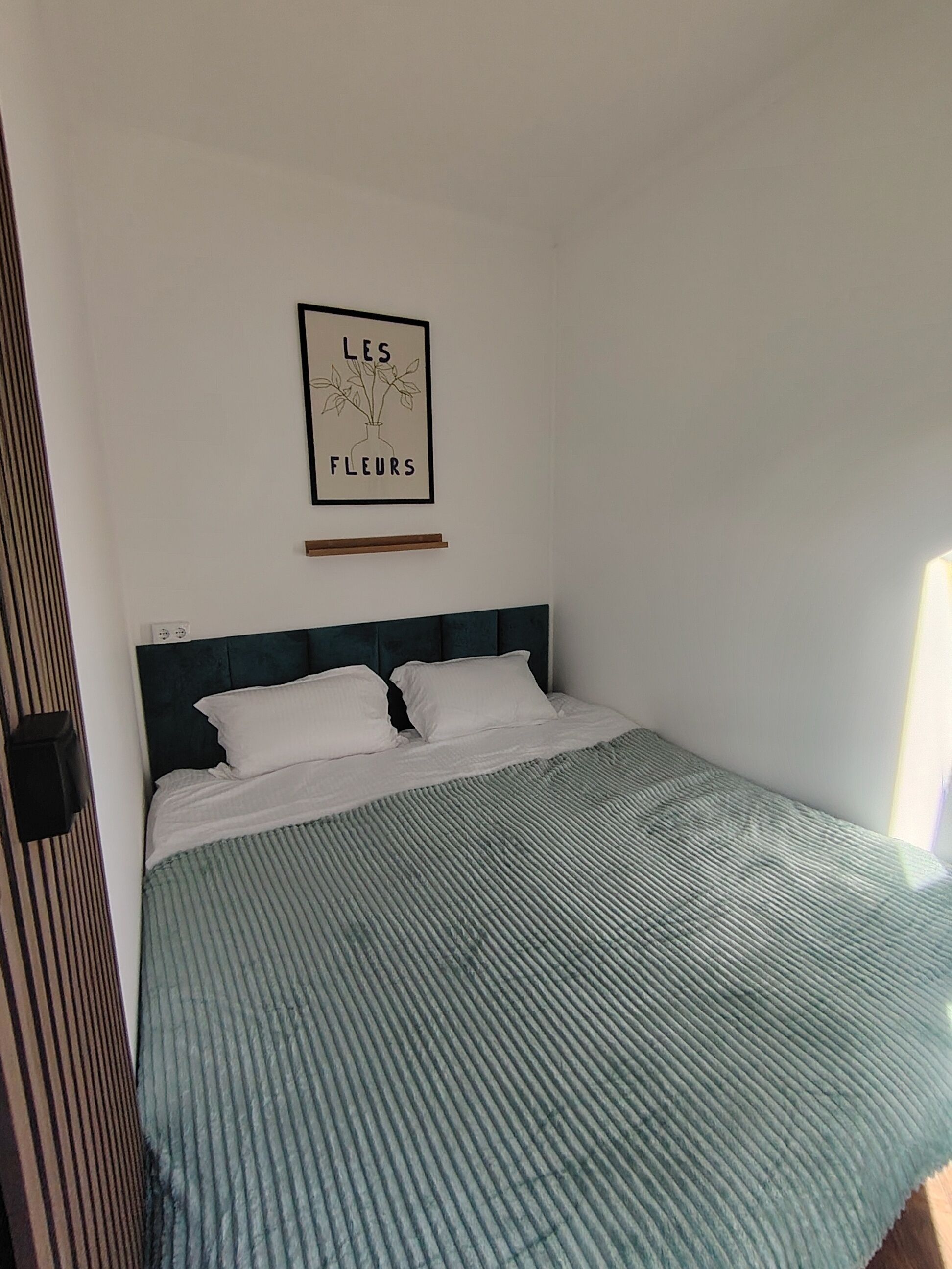 A single bed with a headboard, a bedside table, and a framed picture on the wall.