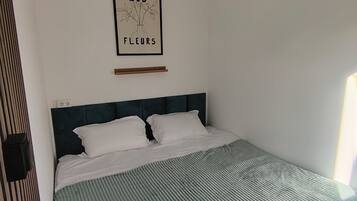 A single bed with a headboard, a bedside table, and a framed picture on the wall.