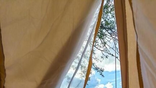 Una carpa con vista a un área cubierta de pasto y otra carpa al fondo.