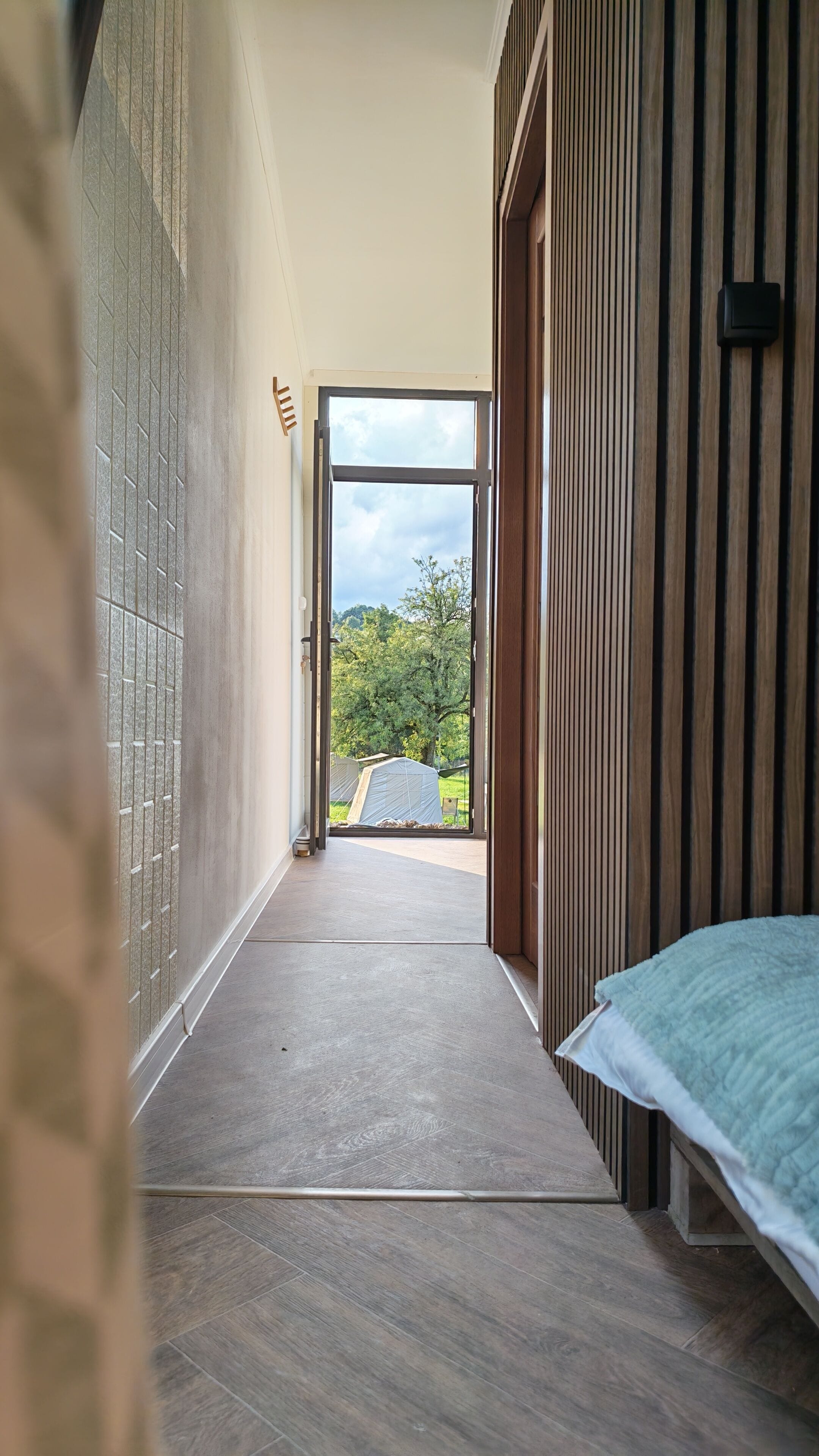 A hallway leading to a bedroom with a bed and a window.