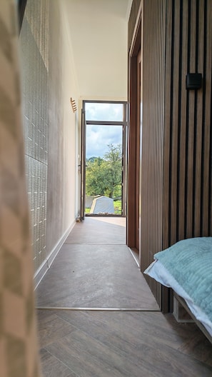A hallway leading to a bedroom with a bed and a window.
