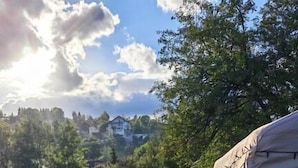 Tienda de campaña instalada en un campo de césped bajo un cielo despejado, con edificios a lo lejos.