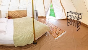Una tienda de campaña con una cama, una mesa y un sillón colgante.