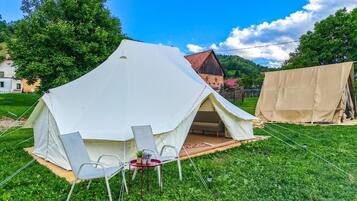 Una carpa con una mesa y sillas dispuestas sobre un césped.