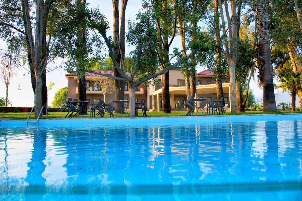 Una piscina con sillas de descanso y un edificio de techo rojo al fondo.