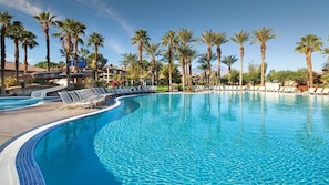 A large, clear swimming pool with lounge chairs and palm trees. - Coachella Rental for 2028 and 2029 (Palm Desert)