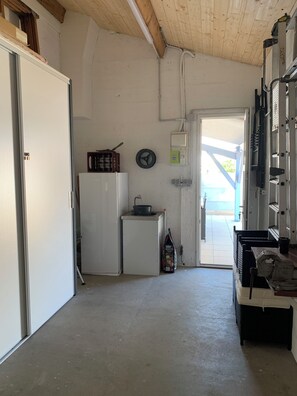 A compact kitchen with a refrigerator, a small sink, and a stove. There is a door leading to an outdoor area. - Fenced detached house 600m from the sea (La tranche sur mer)