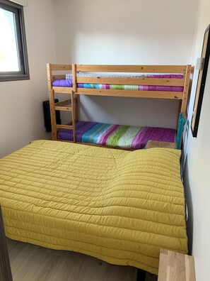 A bunk bed with a yellow quilt, a wooden headboard, and a window to the left. - Fenced detached house 600m from the sea (La tranche sur mer)
