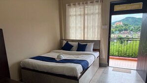 Una habitación de hotel con cama, vista a un balcón y una puerta que da al exterior.