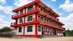 Un edificio de varios pisos con una combinación de colores rojo y blanco, con balcones y techo plano.