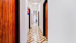 Un pasillo con puertas de madera, un suelo estampado y un extintor en la pared.