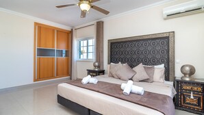 A bedroom with a bed, a ceiling fan, a wardrobe, a window, and an air conditioning unit. - Casa Vista Mar - 2 Bed Apt With Sea Views & Communal Pool (Carvoeiro)