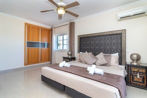 A bedroom with a bed, a ceiling fan, a wardrobe, a window, and an air conditioning unit. - Casa Vista Mar - 2 Bed Apt With Sea Views & Communal Pool (Carvoeiro)