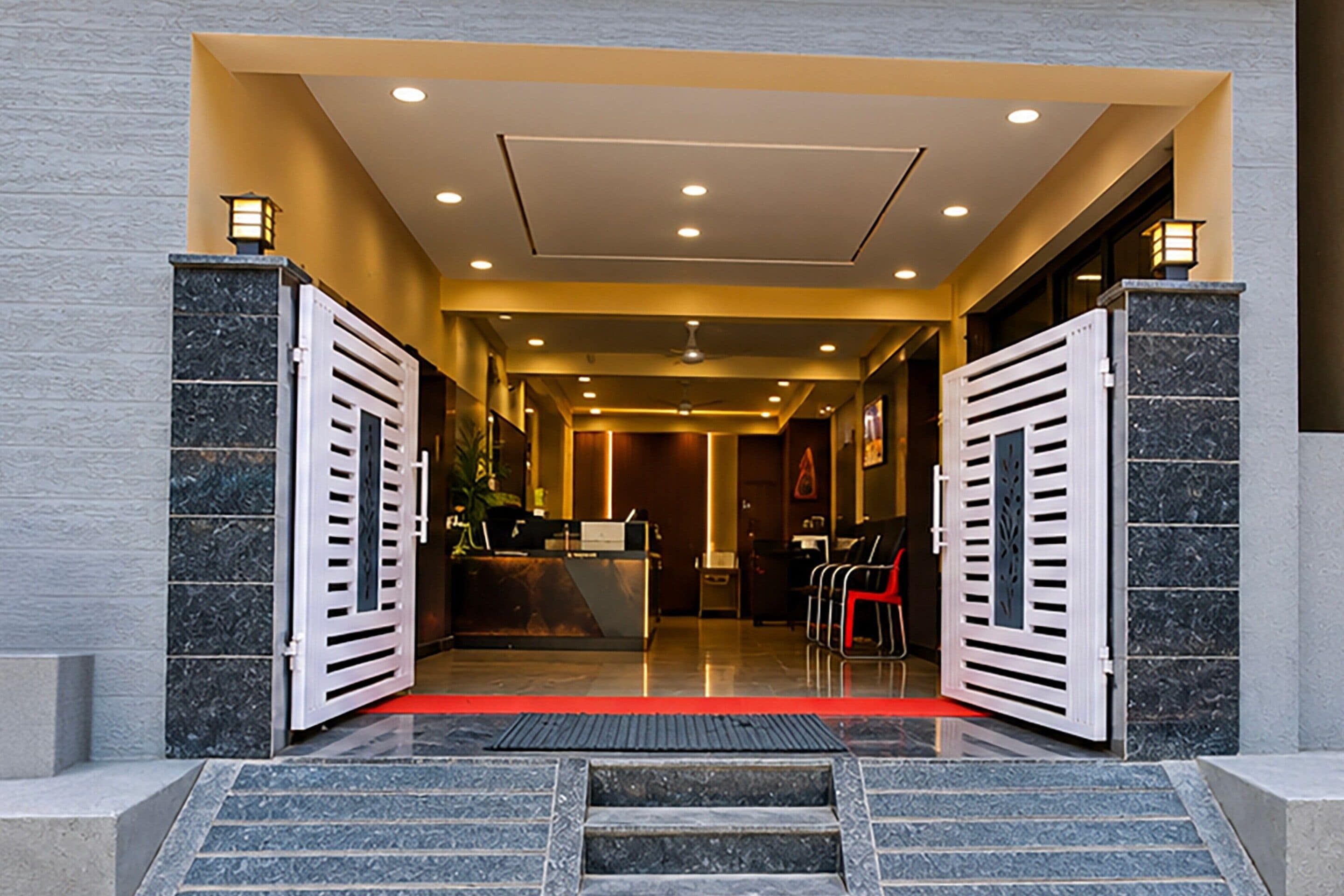 A hotel entrance with a reception desk, a red carpet, and a staircase leading up.