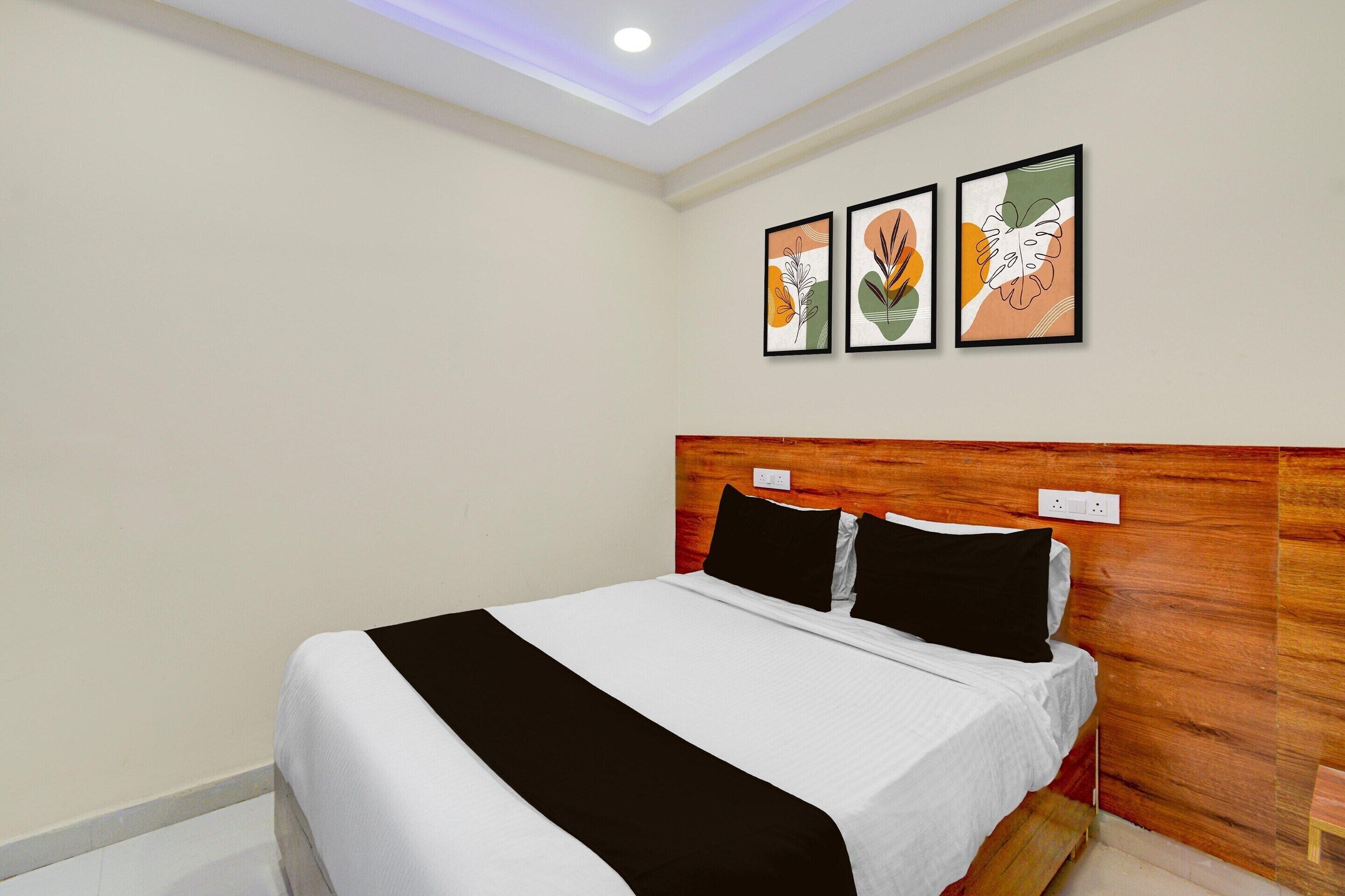 A hotel room with a bed, a wooden headboard, and three framed artworks on the wall.