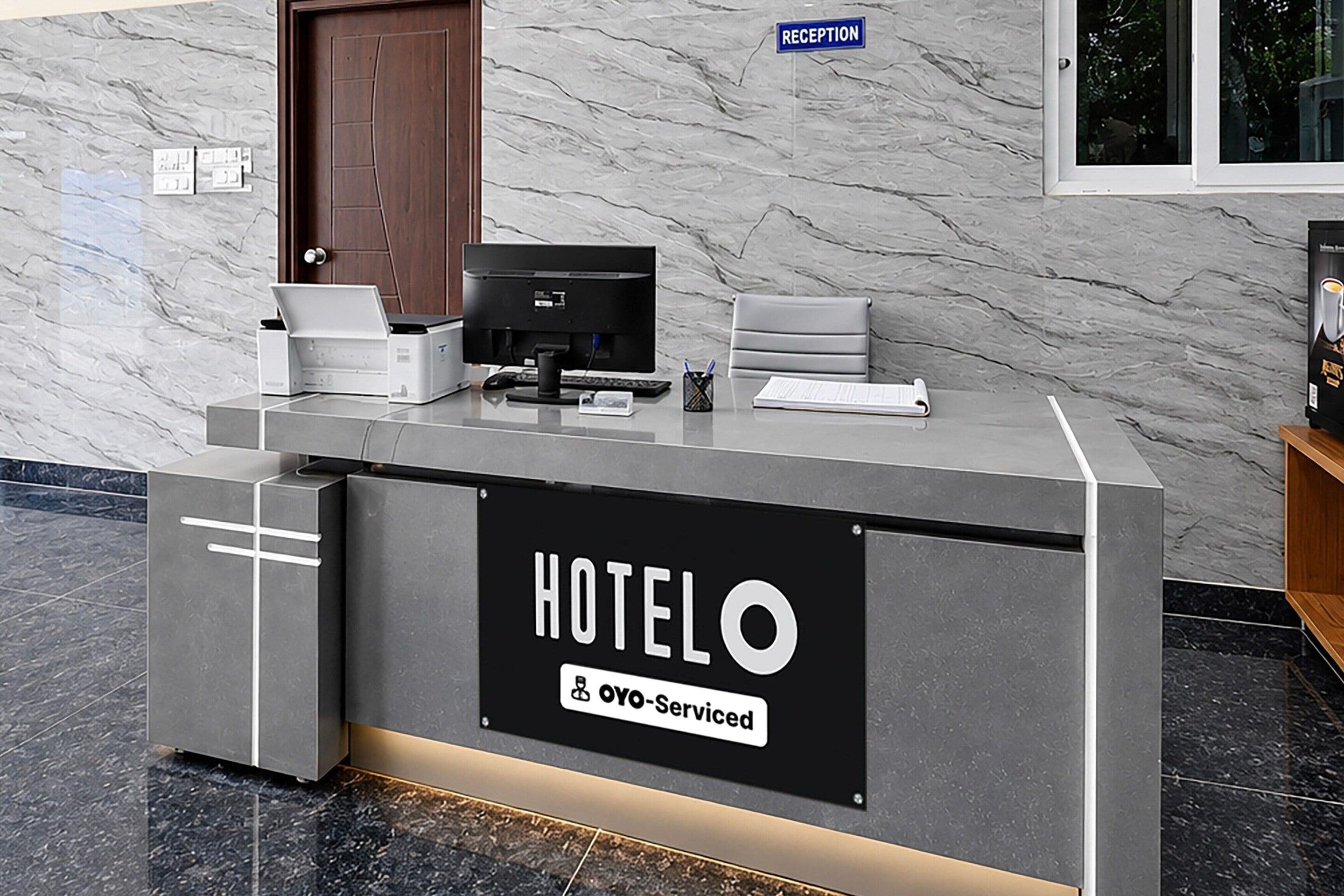 En hotellreception med en skylt som visar texten ”HOTELO & OYO – hotell med service”.