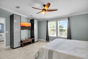 A bedroom with a bed, a ceiling fan, a TV mounted on the wall, and a window with curtains. - Walk to Sombrero Beach - 85' Dock, Views (Marathon)