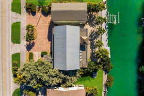 An aerial view of a building with a flat roof, surrounded by greenery and a body of water. - Walk to Sombrero Beach - 85' Dock, Views (Marathon)