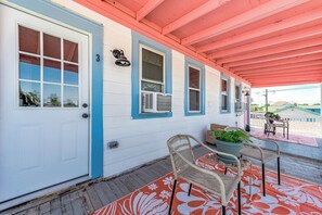 A covered porch with a white door, a number '3' sign, and a row of windows with blue trim. - Coastal Sophistication (Galveston)