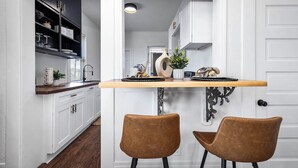 A kitchen with a wooden countertop, two brown chairs, and a potted plant. - Coastal Sophistication (Galveston)