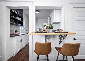 A kitchen with a wooden countertop, two brown chairs, and a potted plant. - Coastal Sophistication (Galveston)