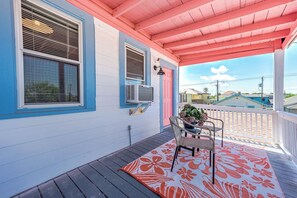 A covered porch with a wooden floor, a chair, and a potted plant. - Coastal Sophistication (Galveston)